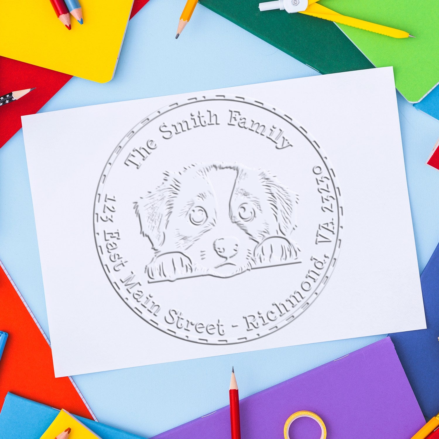 Custom pet stamp seal on white paper with dog design, surrounded by colorful pencils, notebooks, and craft supplies.