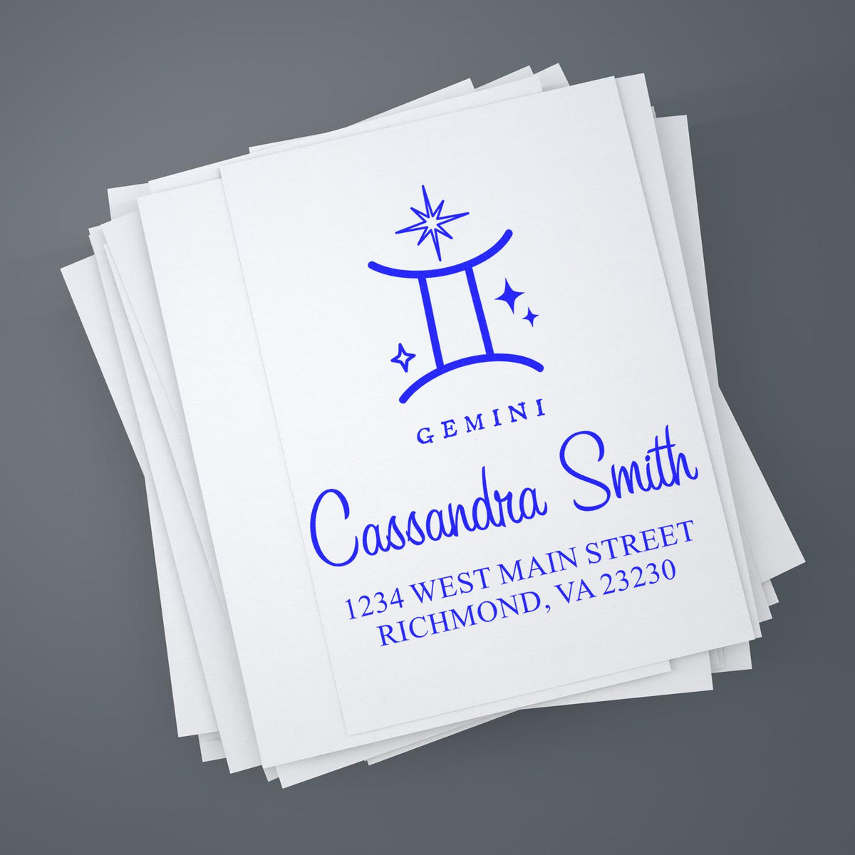 Blue Gemini stamp and seal on stacked white stationery for Cassandra Smith, with address details on a gray background.
