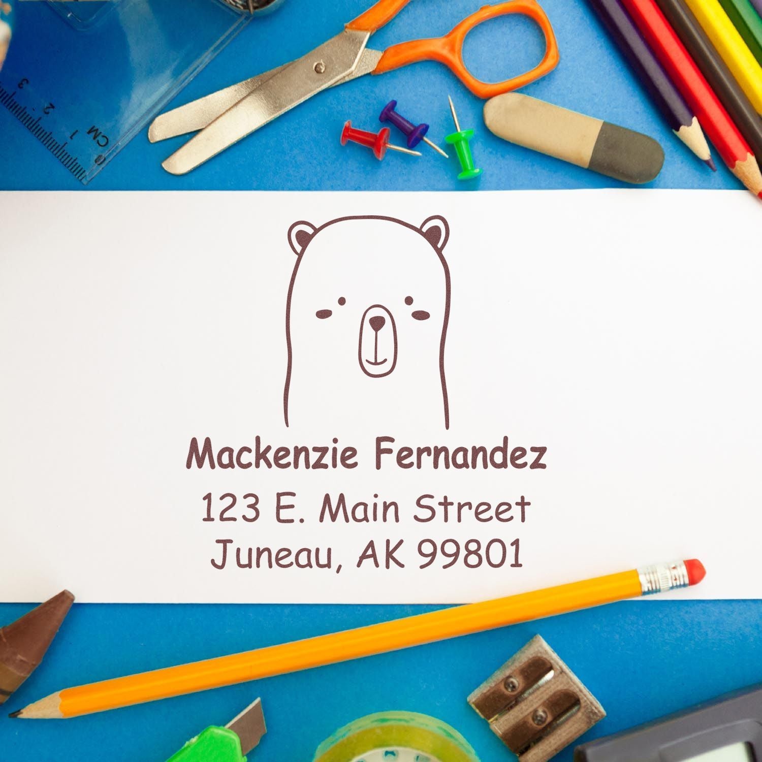 Wood handle adorable bear cartoon animal made to order mail stamp on a personalized home stamp. The stamp features a cute bear design with the name Mackenzie Fernandez and an address, surrounded by colorful stationery items on a blue background.