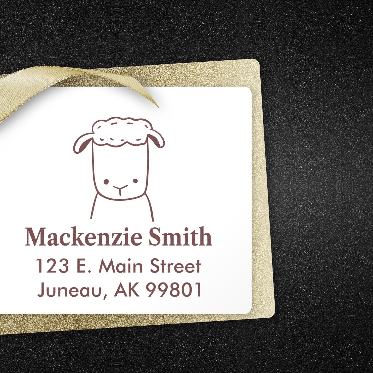 Wood handle fluffy sheep cartoon animal made to order name and address stamper on a card. Custom return mail stamp with a cute sheep design, featuring the name Mackenzie Smith and address 123 E. Main Street, Juneau, AK 99801, on a glittery background.