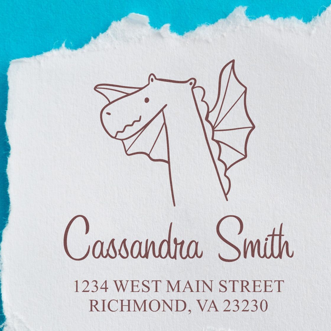Wood Handle Dragon Delight Cartoon Animal Made To Order Return Address Stamper featuring a dragon illustration. Personalizable Return Mail Stamp with the name "Cassandra Smith" and address "1234 West Main Street, Richmond, VA 23230" on torn paper.