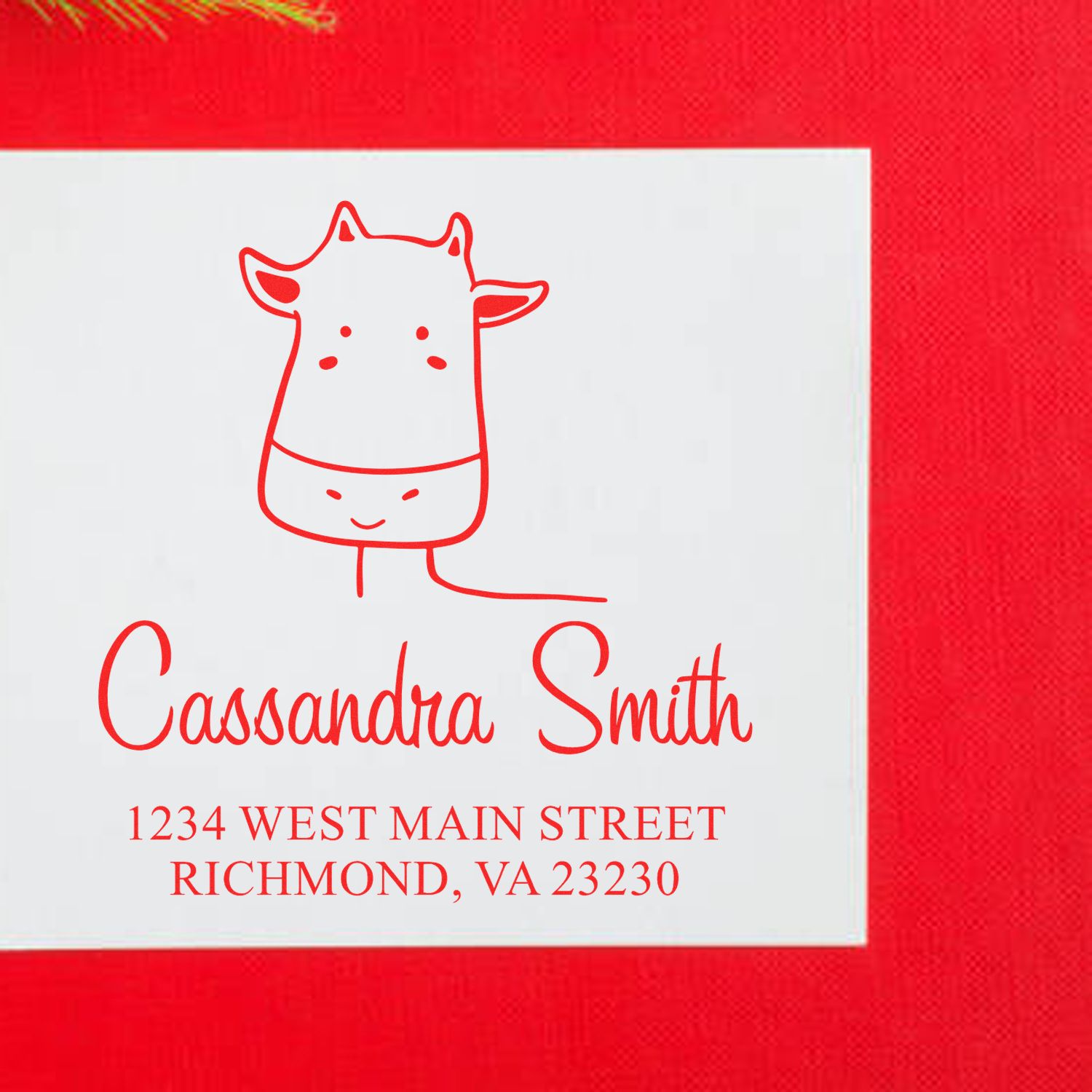 Red envelope with a white card featuring a red giraffe illustration and text: "Cassandra Smith, 1234 West Main Street, Richmond, VA 23230." The Giraffe Grins Pre-Inked Handcrafted Mail Stamp is used as a Customized Home Stamp.