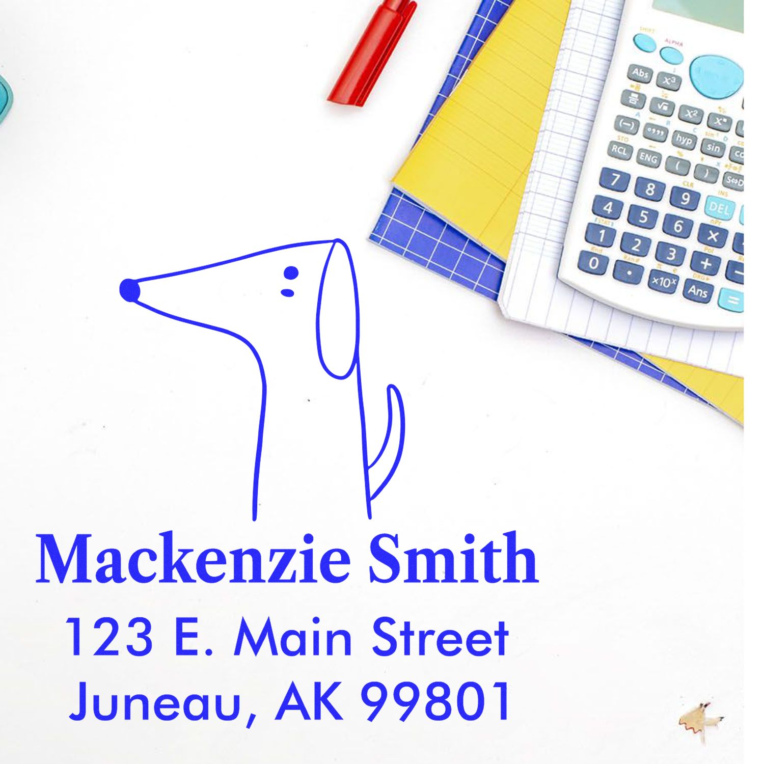 Self-Inking Cartoon Animal Perky Pooch Personalized Address Stamper on a desk with a calculator, notebooks, and a pen. The Personalized Return Mail Stamp features a simple dog illustration and the address: Mackenzie Smith, 123 E. Main Street, Juneau, AK 99801.