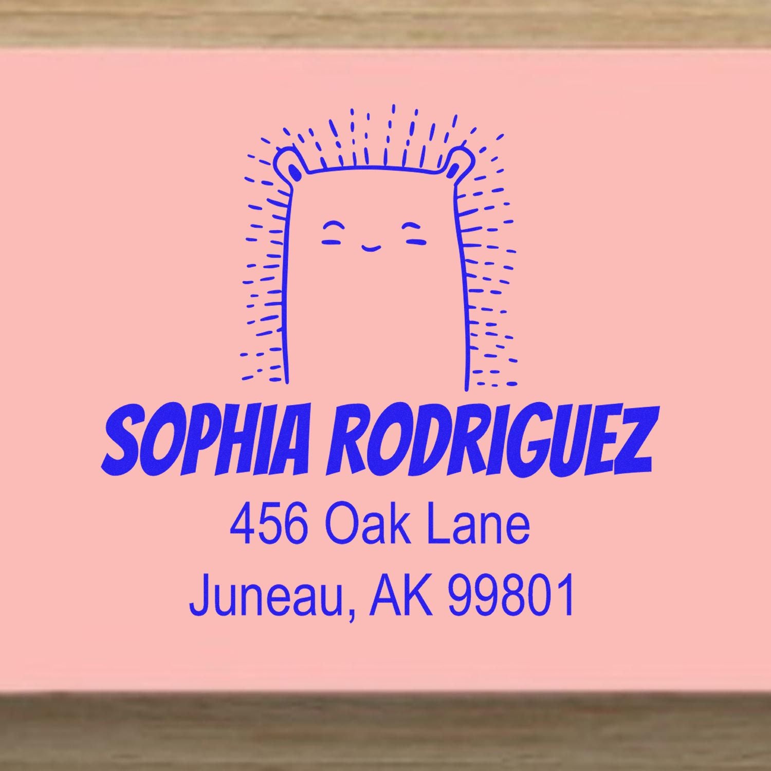 Wood Handle Bouncy Bear Cartoon Animal Custom Address Stamp on pink paper, featuring a smiling bear design. Text reads "Sophia Rodriguez, 456 Oak Lane, Juneau, AK 99801." Personalizable Address Stamp with blue ink and playful font.