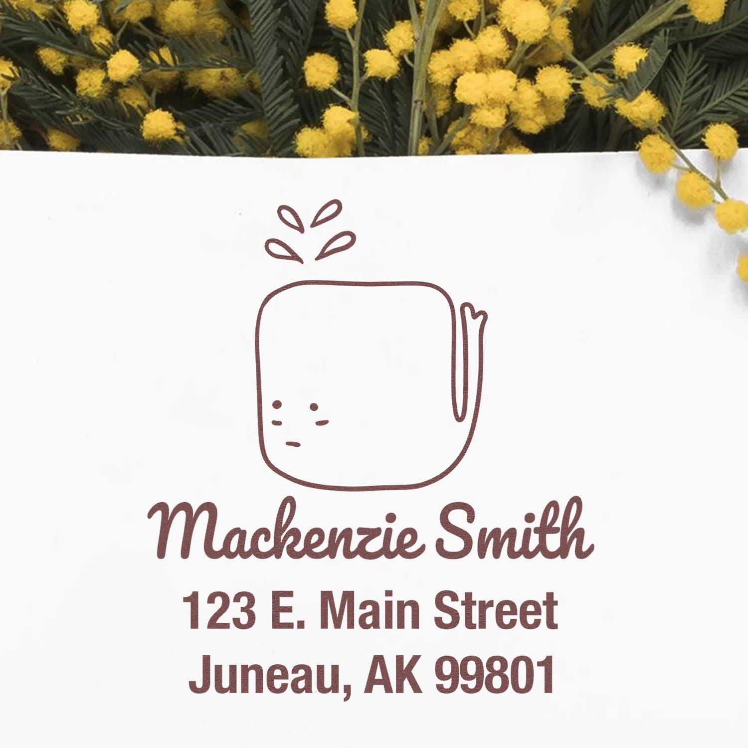 Wood handle joyful whale cartoon animal custom home stamp on an envelope. The custom-made address stamp features "Mackenzie Smith, 123 E. Main Street, Juneau, AK 99801" with yellow flowers in the background.