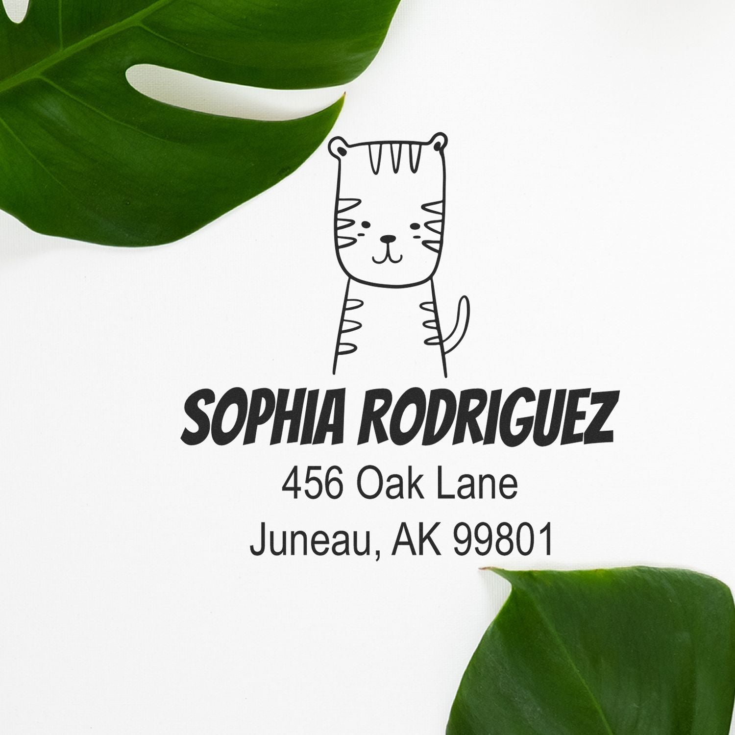 Wood handle terrific tiger cartoon animal custom return address stamper on white paper. The customized return mail stamp features a cute tiger illustration above the name "Sophia Rodriguez" with an address in Juneau, AK, surrounded by green leaves.