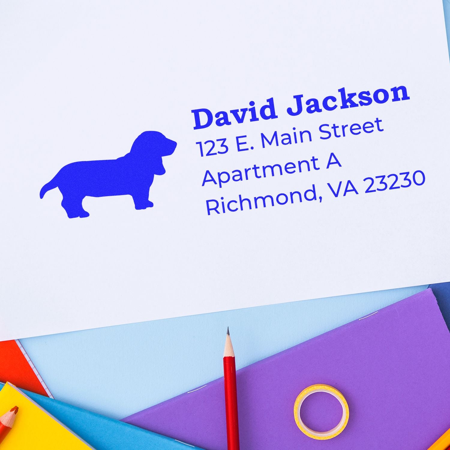 PSI Pre-Inked Personalized Basset Hound Address Stamp on white paper with blue dog silhouette, colorful stationery, and text: David Jackson, 123 E. Main Street, Apartment A, Richmond, VA 23230.