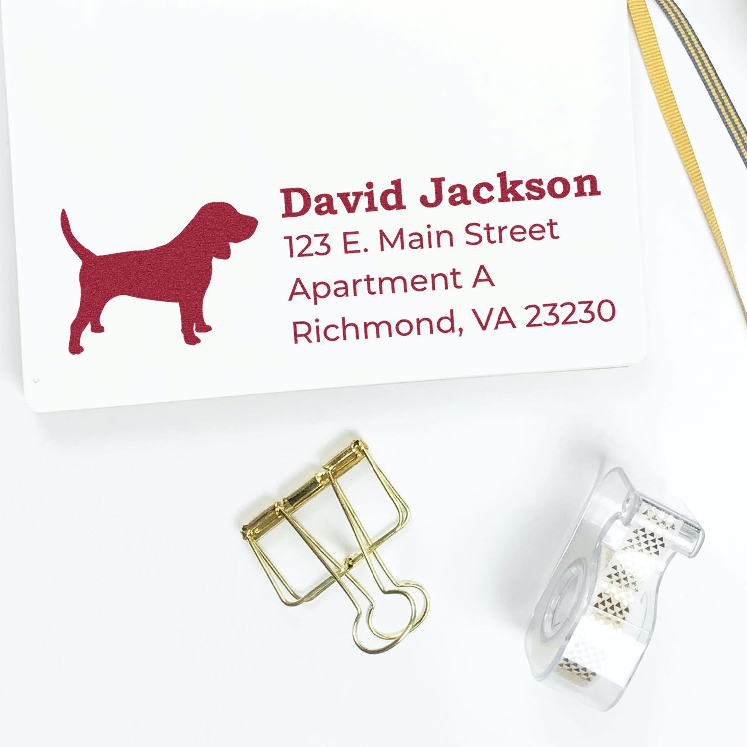 Beagle Silhouette Address Rubber Stamp on white paper with red beagle design and sample address. Nearby are a gold binder clip and decorative tape.