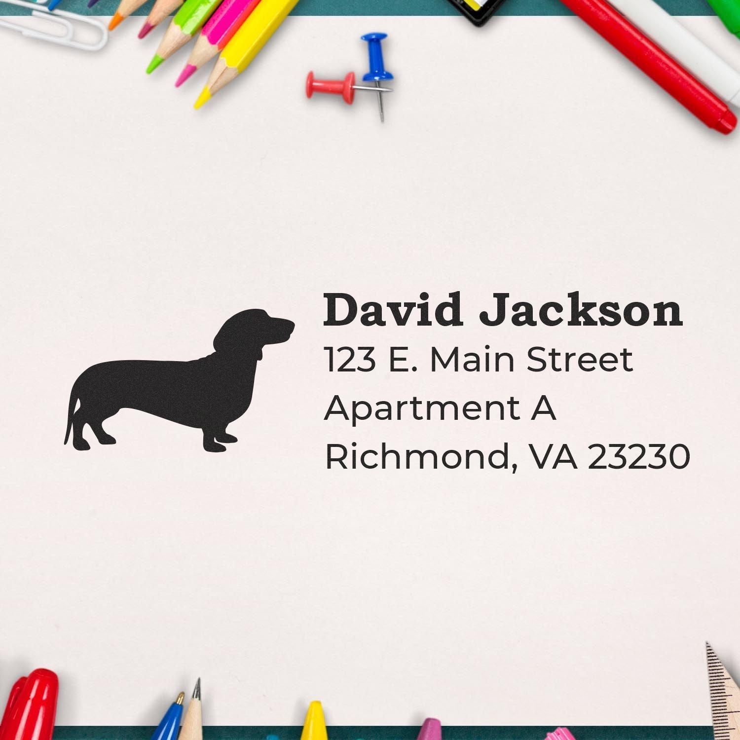 Slim Pre-Inked Dachshund Address Stamp on paper with colorful stationery. Features a dachshund silhouette and sample address text. Perfect for adding a personal touch to mail and documents.