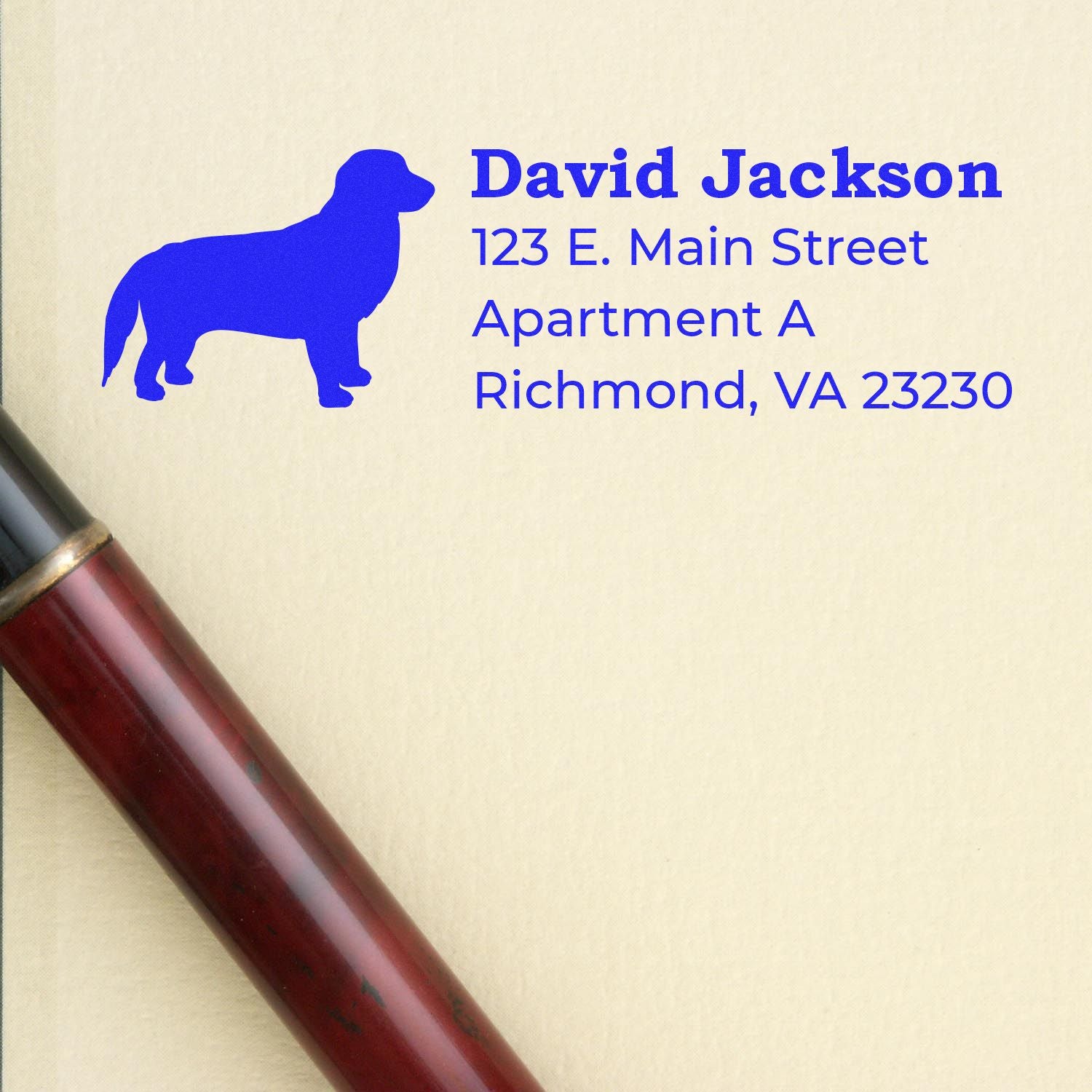 Golden Retriever Silhouette Address Rubber Stamp on paper with a pen nearby, featuring a blue dog silhouette and sample address text in bold font.