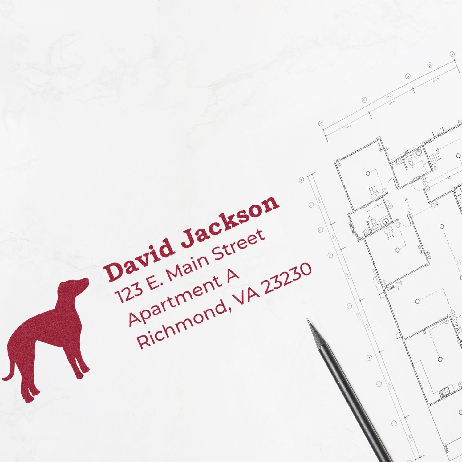 Self-Inking Whippet Dog Address Stamp on white paper next to a floor plan and pen. The stamp features a red silhouette of a whippet and sample address text in bold red font.