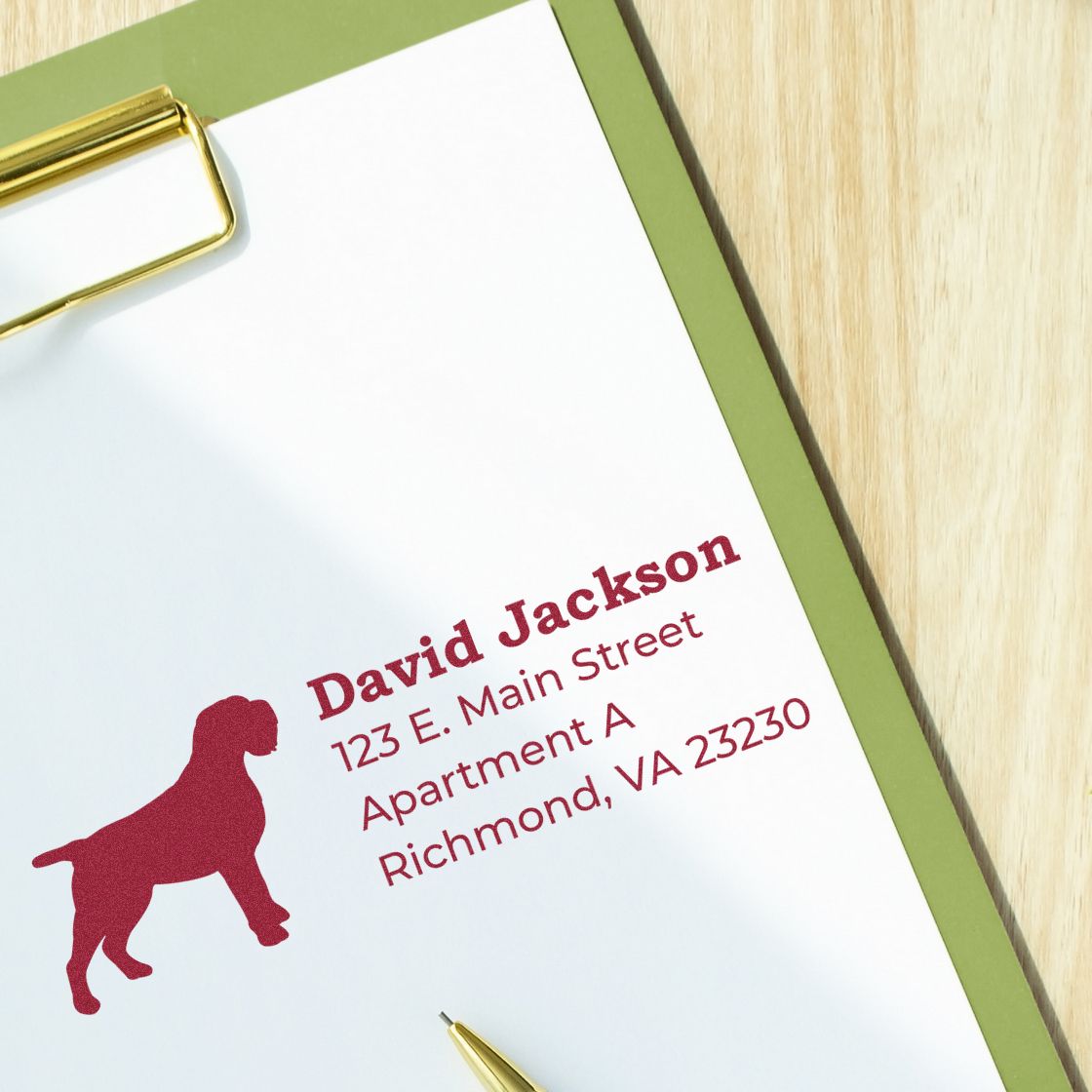 Clipboard with a stamped address featuring a Wirehaired Pointing Griffon silhouette. Text reads David Jackson, 123 E. Main Street, Apartment A, Richmond, VA 23230. PSI Pre-Inked Personalized Address Stamp.