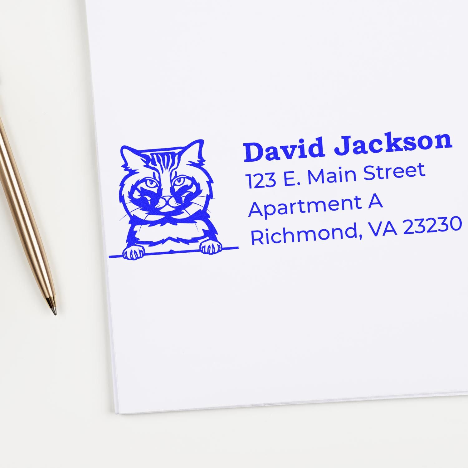 PSI Pre-Inked Peeking American Bobtail Cat Personalized Address Stamp on white paper, featuring a blue cat illustration and sample address text. Pen nearby.