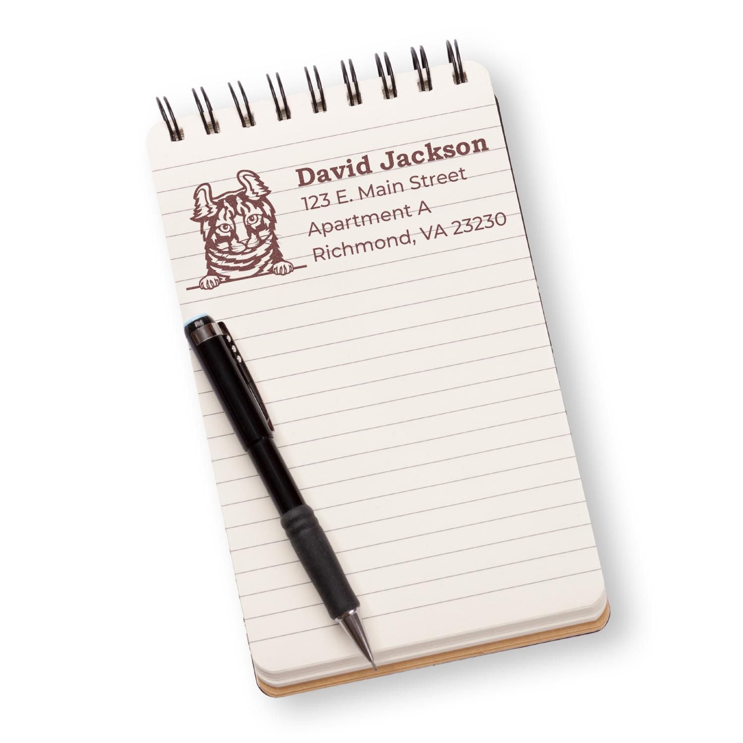 Wood Handle Highlander Cat Address Stamp imprint on a notepad, featuring a cat illustration and sample address. A black pen rests on the notepad, showcasing the stamp's clear, detailed design.