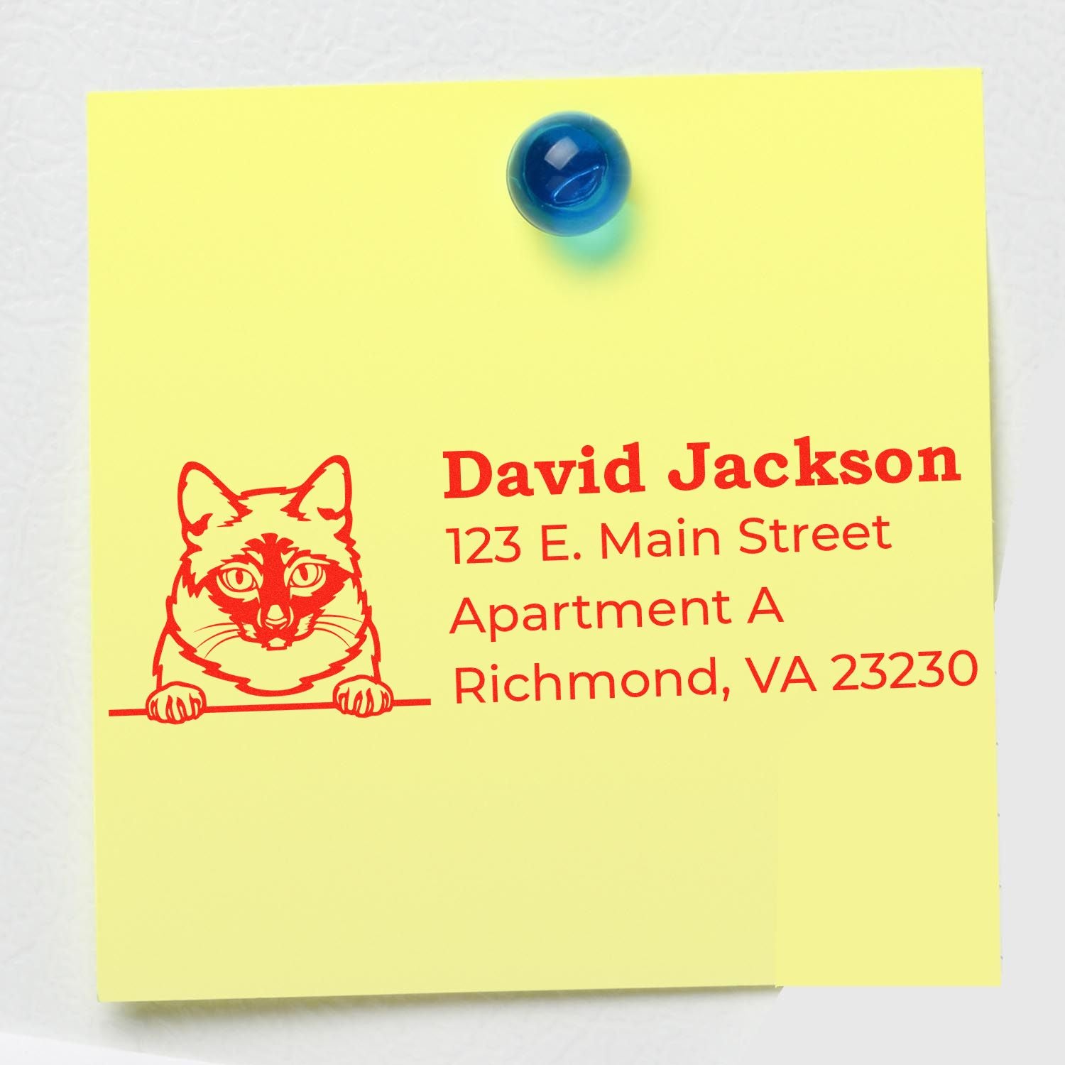 Yellow sticky note with a red cat illustration and address details, showcasing the Slim Pre-Inked Mekong Bobtail Peeking Cat Return Address Stamp, pinned with a blue magnet.