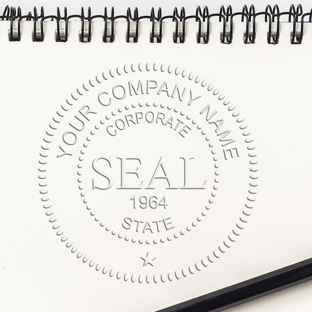 White spiral notebook page with embossed circular company seal stamp, black binding, and gray corporate-style lettering.