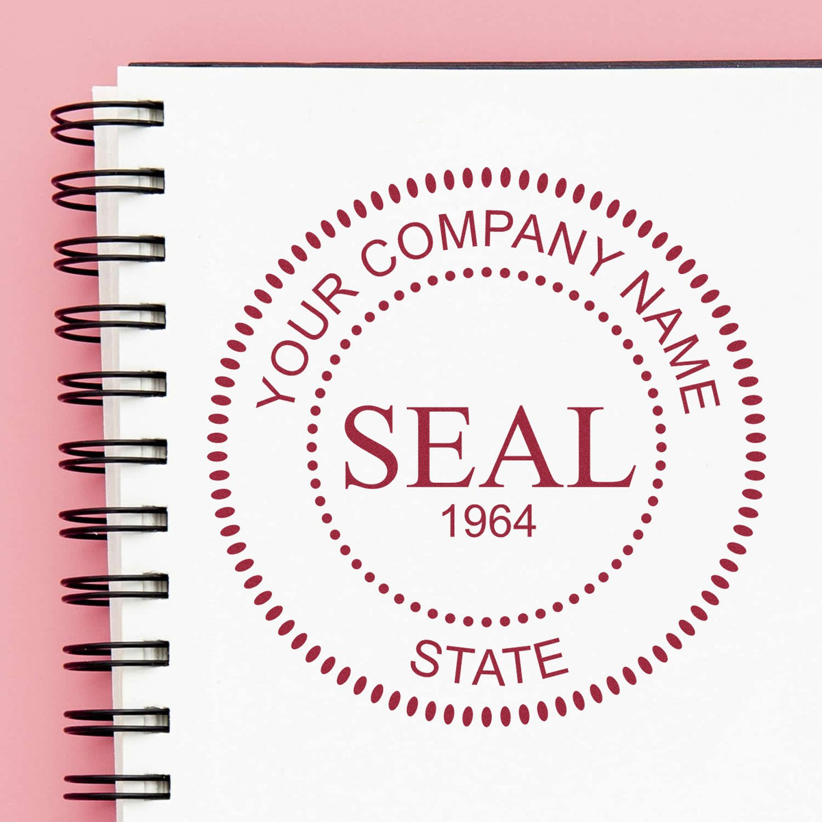 Burgundy custom stamp and seal design on white spiral notebook, with dotted circle border and pink background.