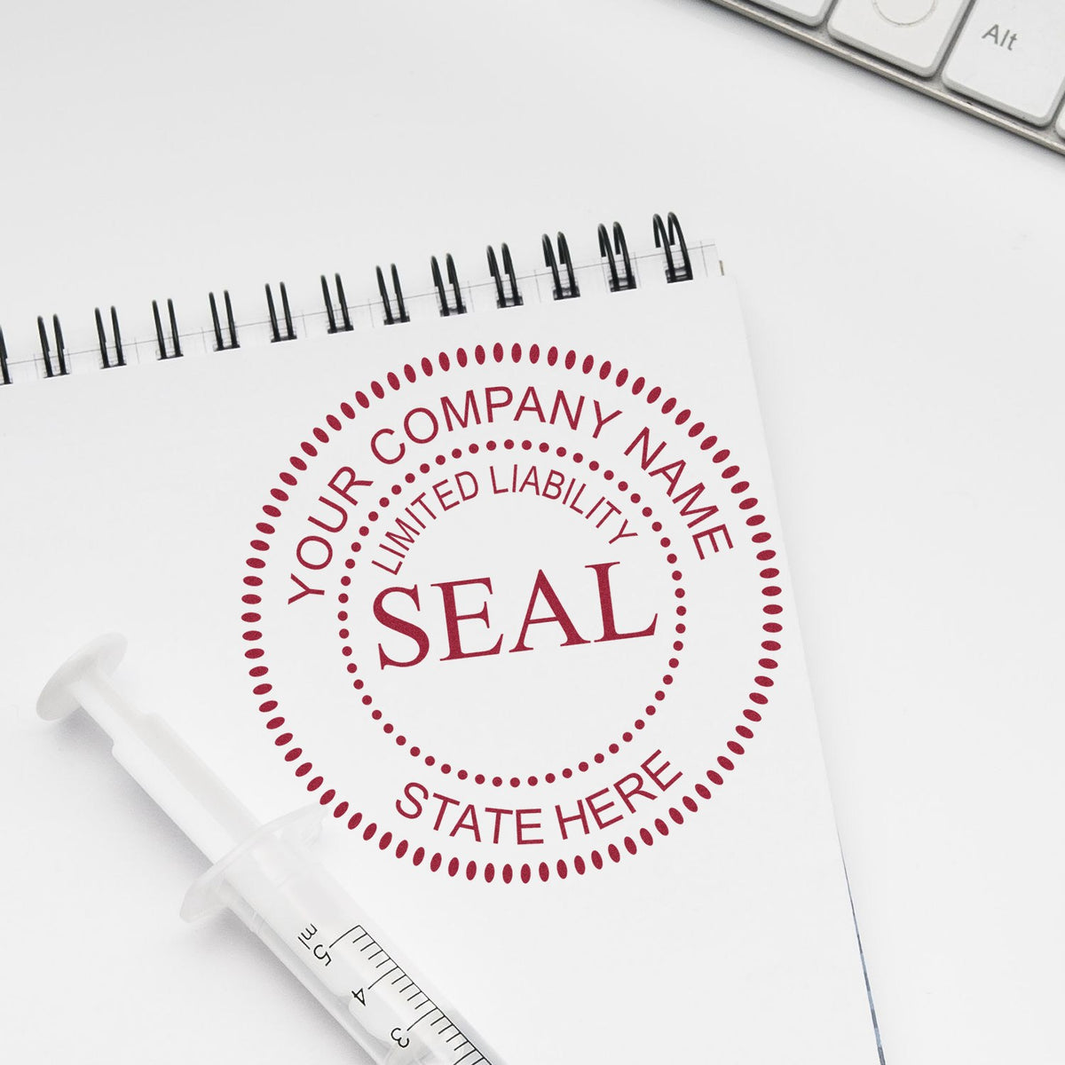 Custom red company seal stamp on a spiral notebook, with a white rubber stamp on a clean white desk.