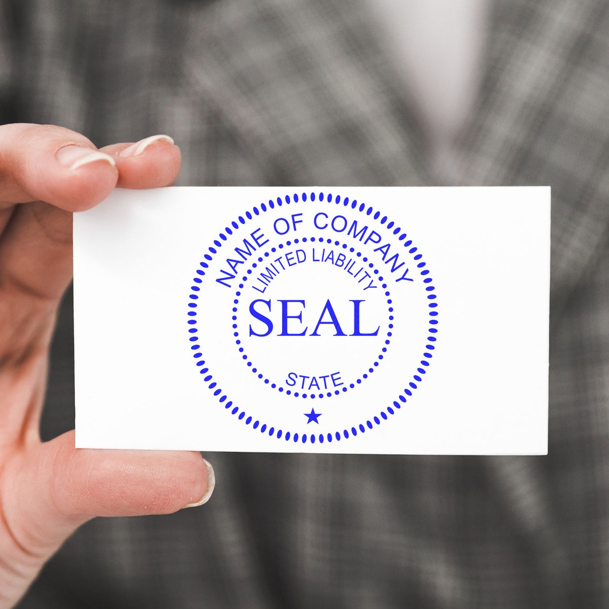 Hand holding white business seal card with blue circular company stamp, SEAL, Name of Company, Limited Liability, and star.
