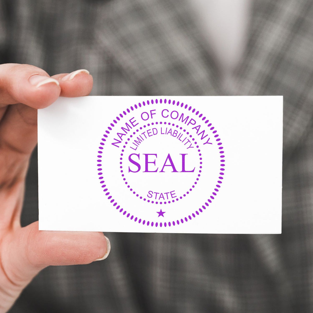 Hand holding a white card with a purple company seal stamp, dotted circle, star, and company-name text.