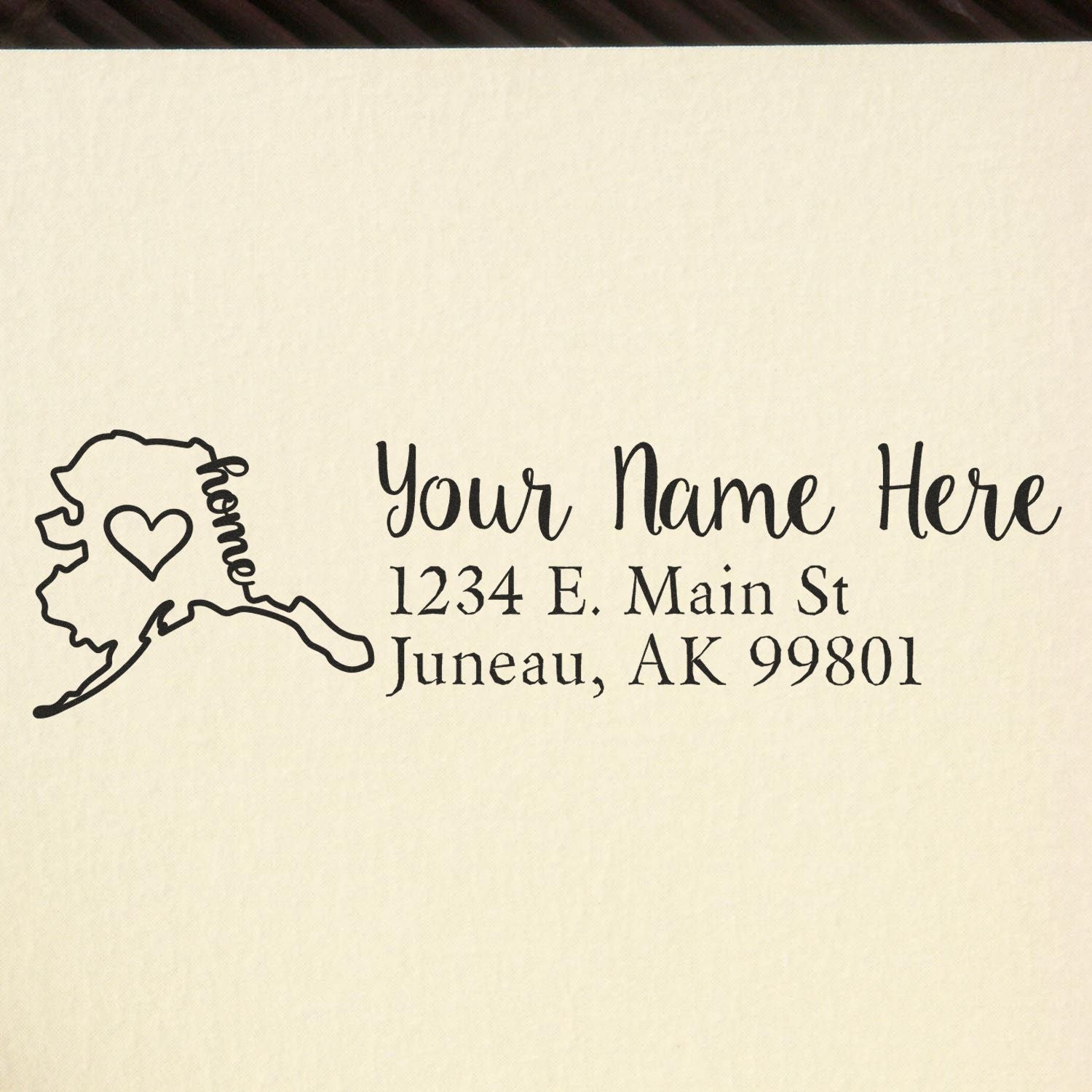 Slim Pre-Inked Alaska State Love Custom Address Stamp on paper, featuring a heart within the Alaska outline and customizable text for name and address in elegant font.