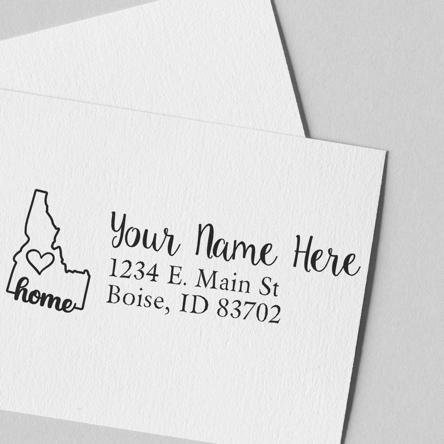 Slim Pre-Inked Idaho State Love Custom Address Stamp on white paper, featuring a heart inside Idaho's outline with home text, personalized with name and Boise, ID address.