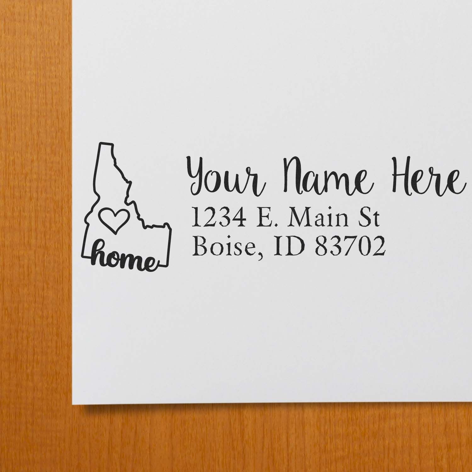 Idaho Self-Inking State Love Address Stamp on white paper, featuring a heart inside the Idaho state outline with home text, and customizable address lines in elegant script.