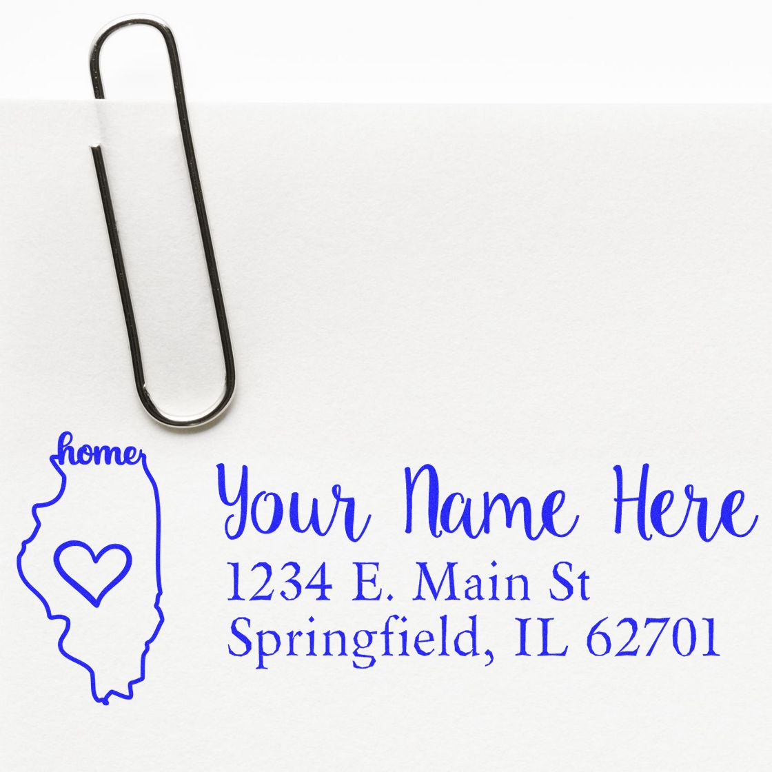 Illinois Self-Inking State Love Address Stamp on paper with a paperclip, featuring a heart design and sample address in blue ink.