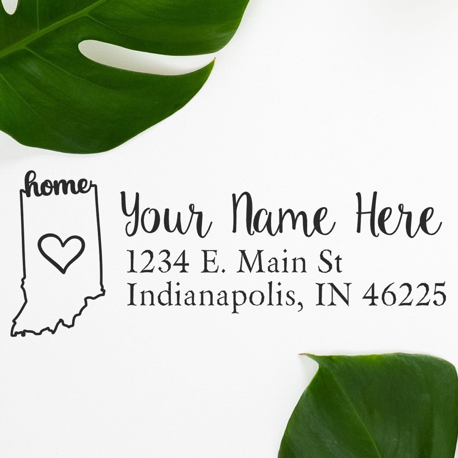 Indiana Self-Inking State Love Address Stamp on white paper with a heart design, featuring customizable address text. Surrounded by green leaves for a stylish presentation.