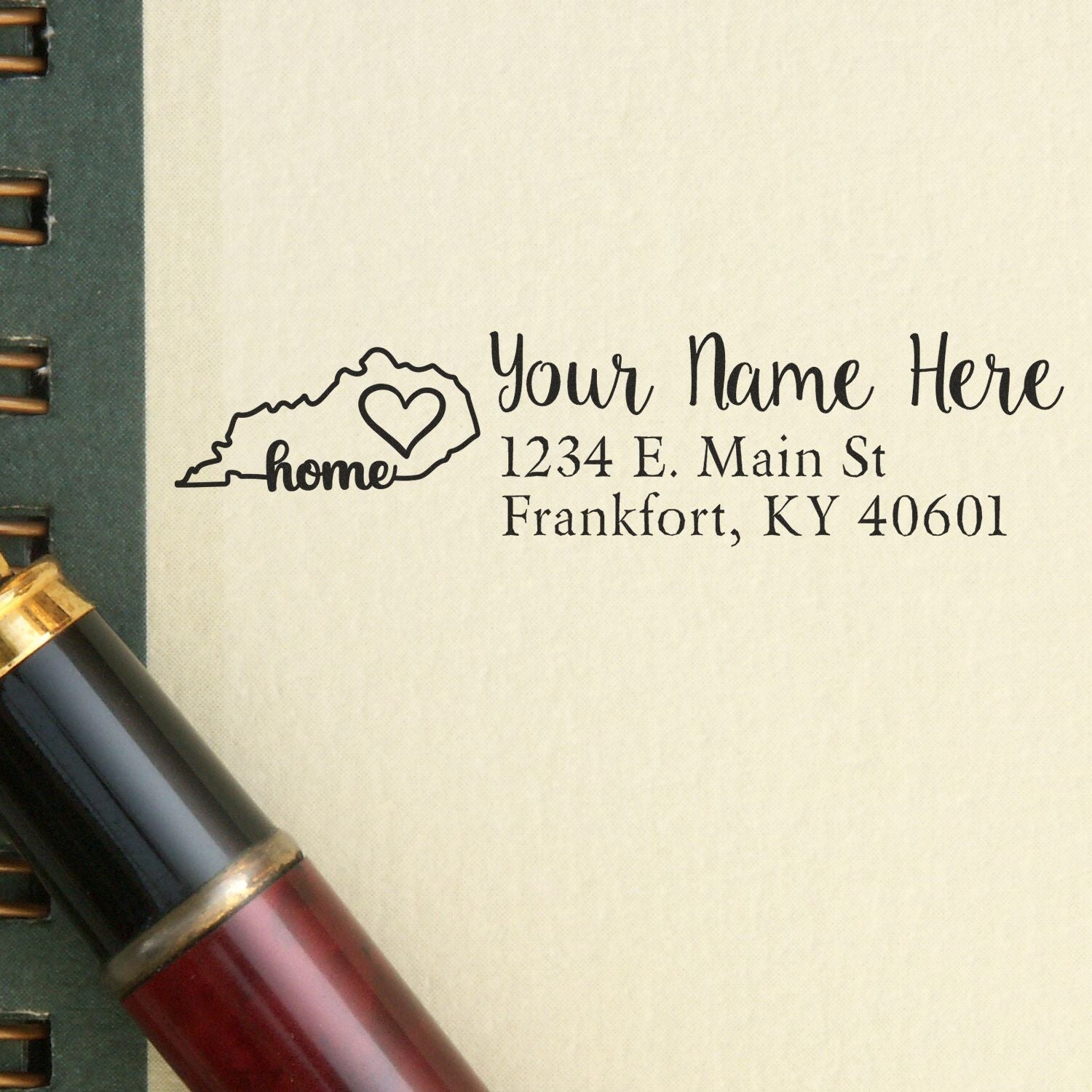 PSI Pre-Inked Personalized Kentucky State Love Address Stamp on paper with a pen, featuring a heart design and customizable address for Frankfort, KY.