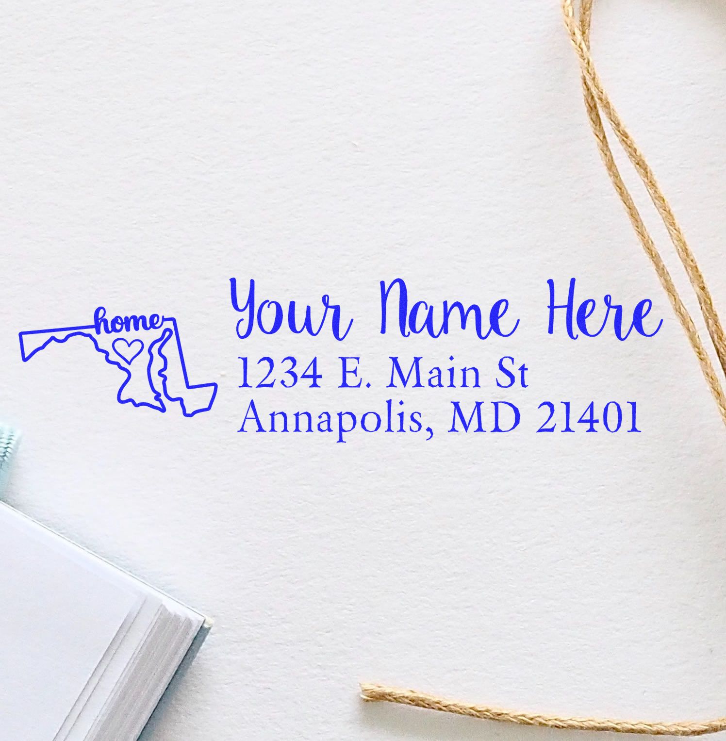 Maryland Self-Inking State Love Address Stamp in blue ink on white paper, featuring a map outline with a heart and the word home, alongside customizable address text.