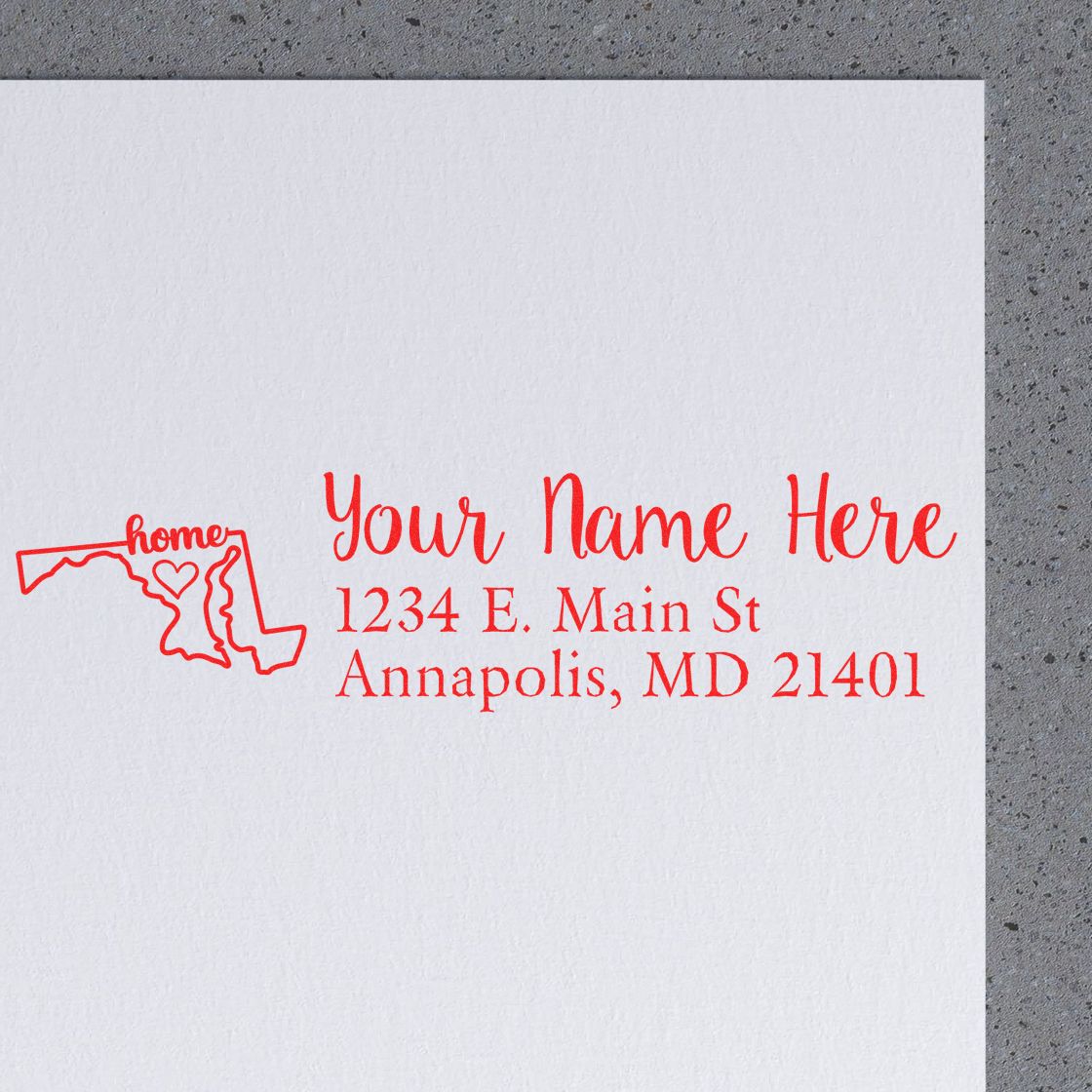 Wood Handle Maryland Custom Address Rubber Stamp on paper, featuring a red outline of Maryland with home text and a heart, alongside customizable address and name in red font.