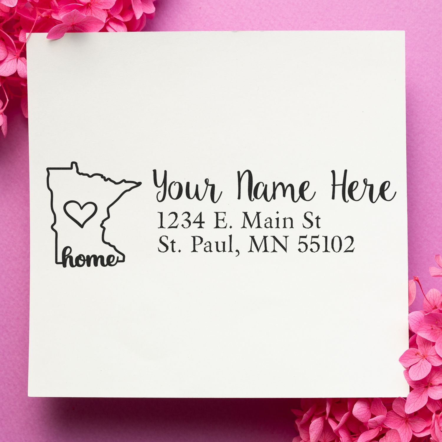 Minnesota Self-Inking State Love Address Stamp on white paper with a heart inside the state outline, text Your Name Here, 1234 E. Main St, St. Paul, MN 55102 on a pink background with flowers.