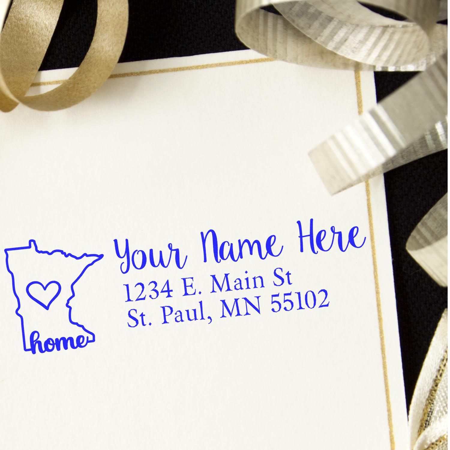 Wood Handle Minnesota Custom Address Rubber Stamp on a card with a blue imprint of a Minnesota outline, heart, and address. Surrounded by gold ribbons, showcasing elegant and personalized stationery.