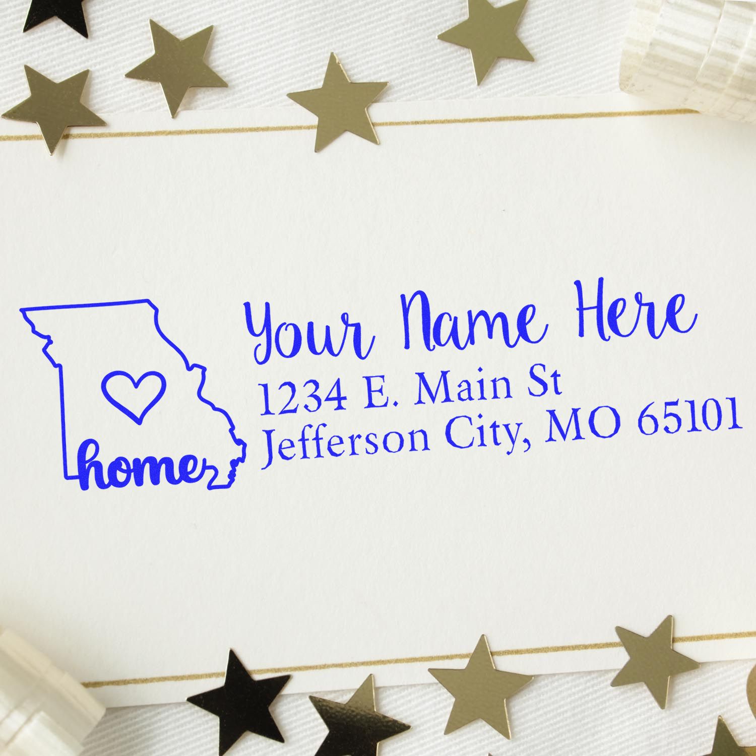 Missouri Self-Inking State Love Address Stamp on white paper with a blue design featuring a heart inside the state outline, surrounded by gold and black star decorations.