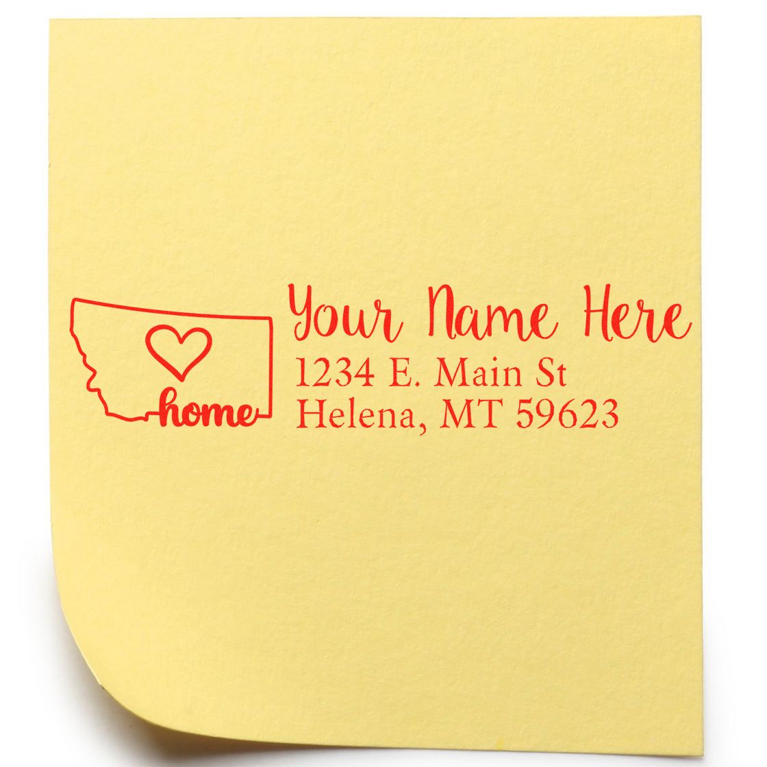 Wood Handle Montana Custom Address Rubber Stamp on yellow paper, featuring a red outline of Montana with a heart and sample address text: Your Name Here, 1234 E. Main St, Helena, MT 59623.