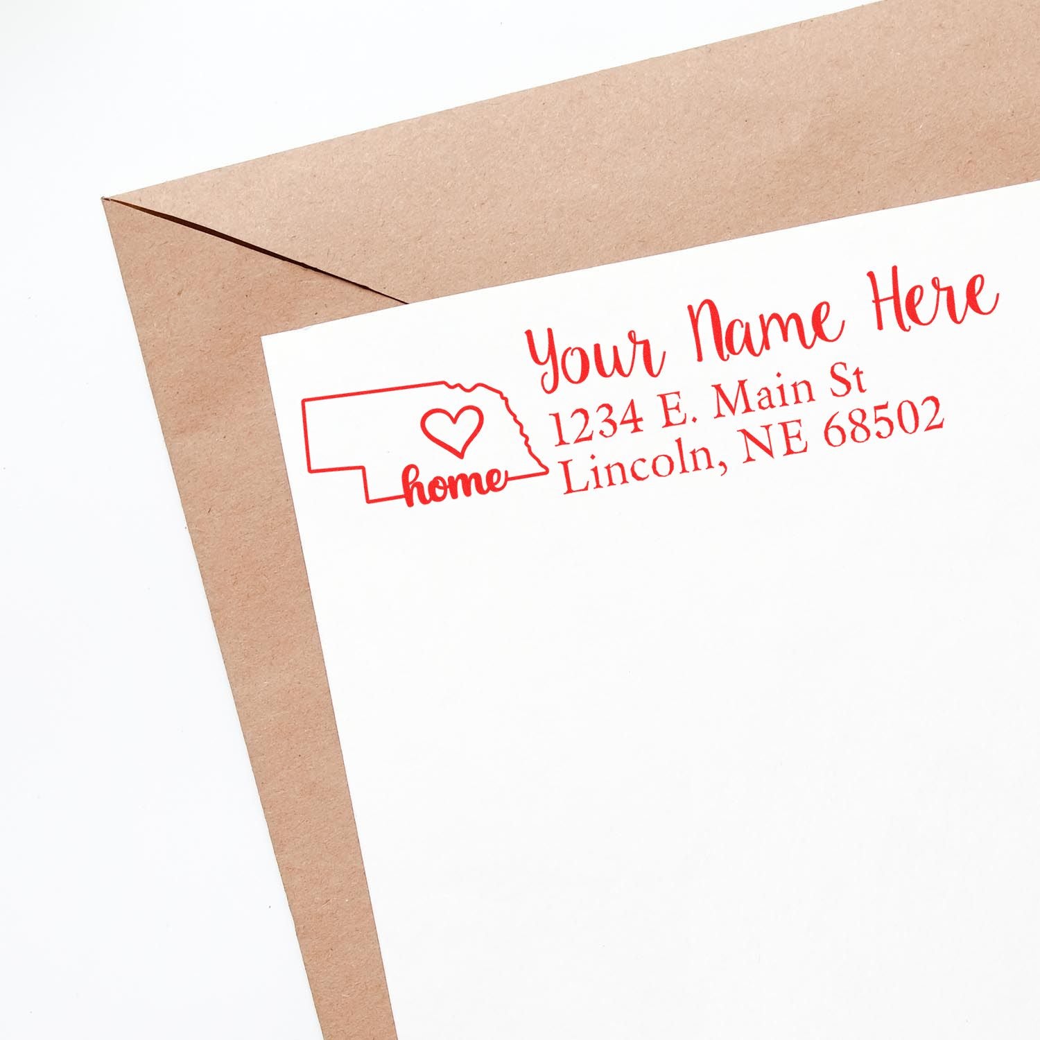 Wood Handle Nebraska Custom Address Rubber Stamp on white paper with red ink, featuring a Nebraska outline and heart design, next to a brown envelope.