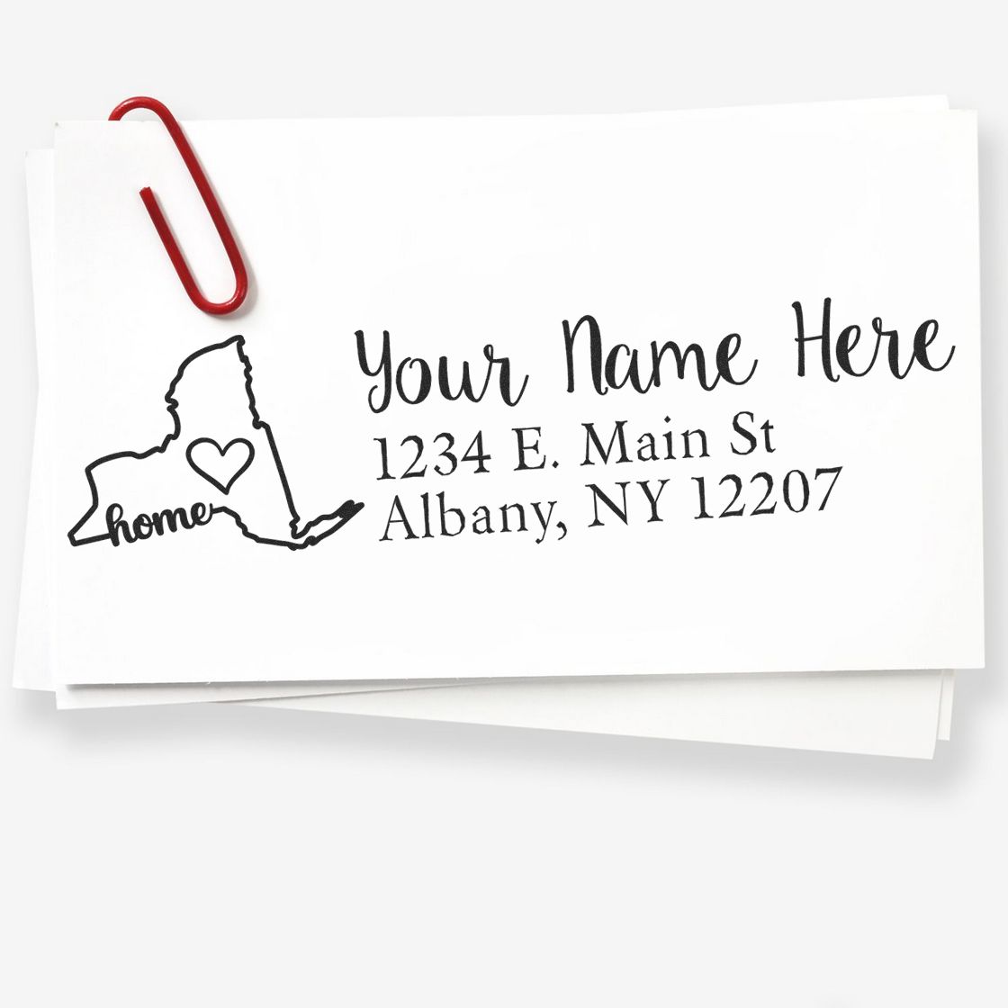 Wood Handle New York Custom Address Rubber Stamp imprint on white paper, featuring a heart inside a New York state outline, with placeholder text for name and address, clipped with a red paperclip.