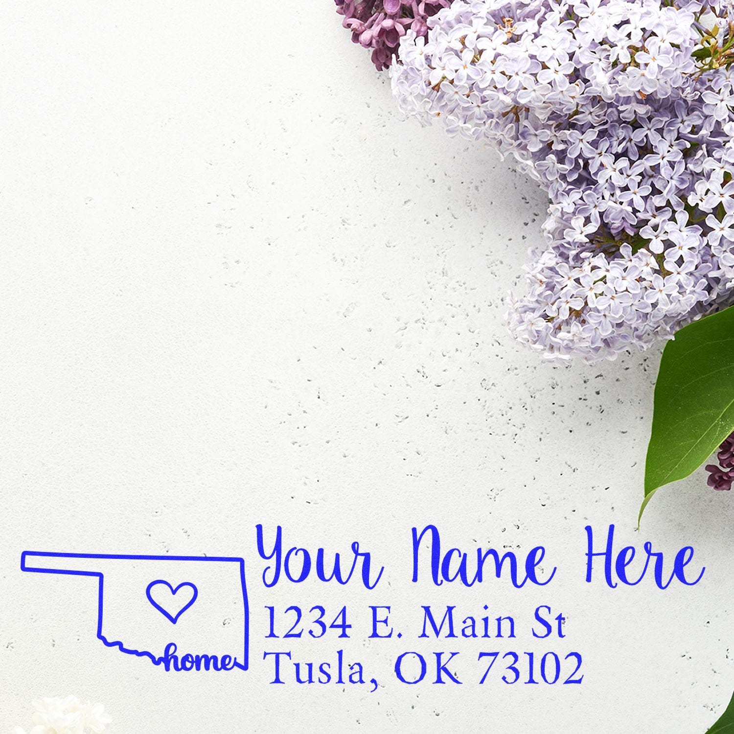 Wood Handle Oklahoma Custom Address Rubber Stamp on white paper with purple lilac flowers. The stamp features a heart inside the Oklahoma state outline, personalized with name and address.