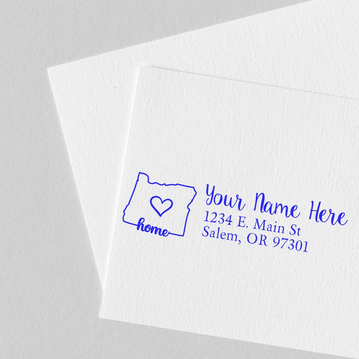 Oregon Self-Inking State Love Address Stamp on white paper, featuring a heart inside the Oregon state outline with customizable address text in blue.