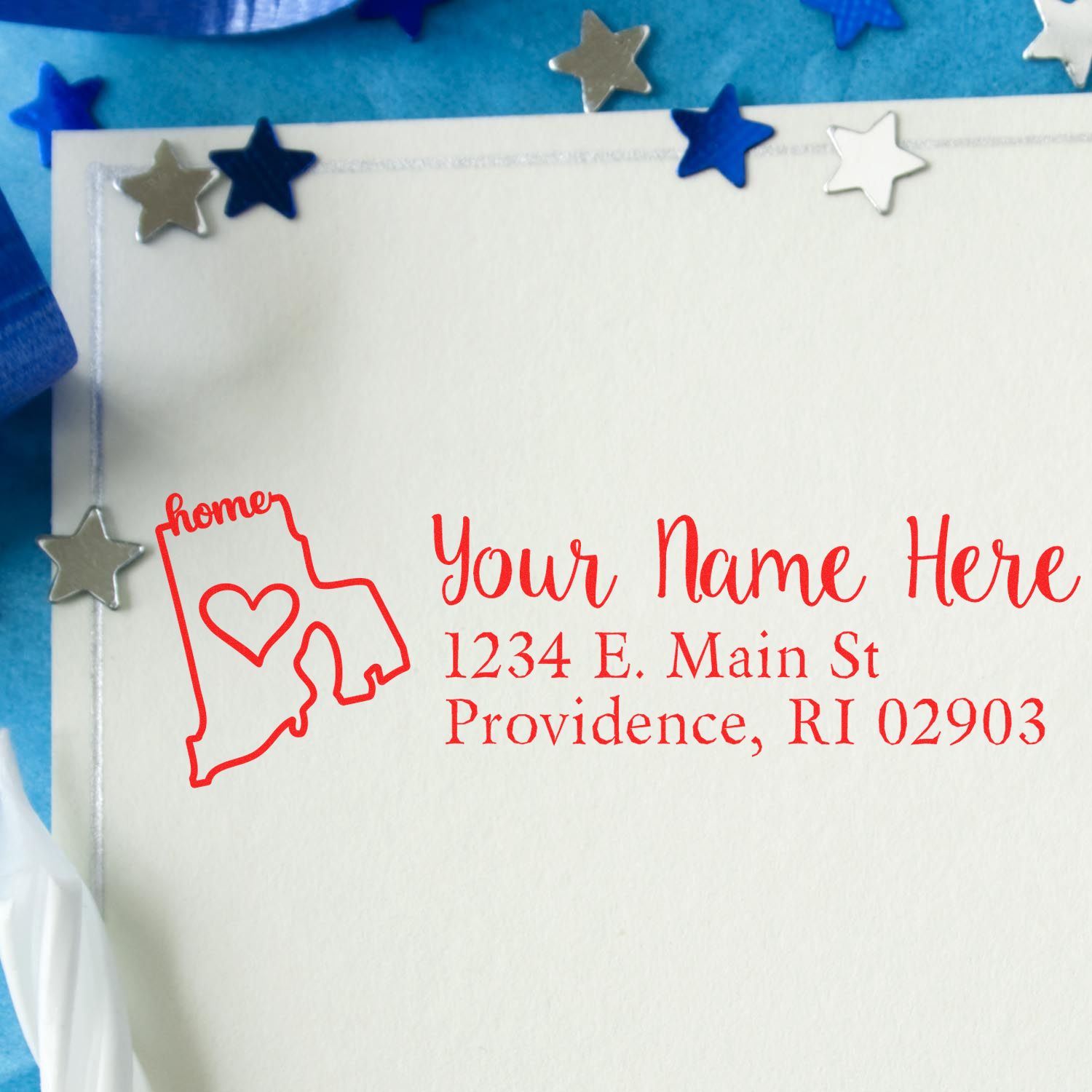 Wood Handle Rhode Island Custom Address Rubber Stamp on an envelope, featuring a red design with a heart and home text, surrounded by blue and silver star decorations.