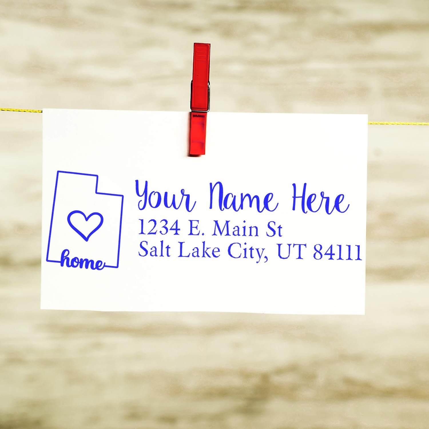 Slim Pre-Inked Utah State Love Custom Address Stamp on white card with red clip, featuring a heart inside Utah outline and sample address in blue text.