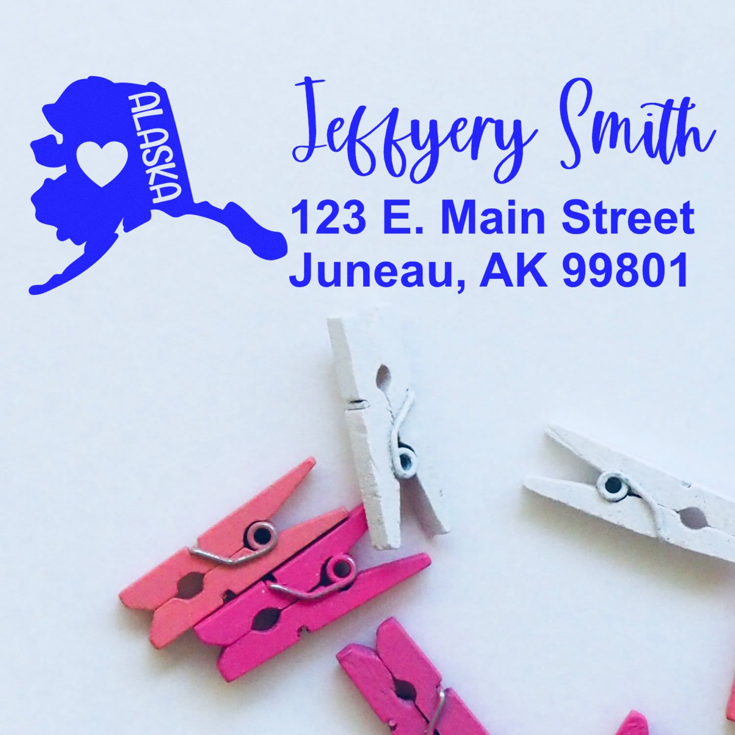 Alaska State Love Personalized Address Stamp featuring a blue Alaska map with a heart, personalized with Jeffery Smith, 123 E. Main Street, Juneau, AK 99801, alongside colorful clothespins.