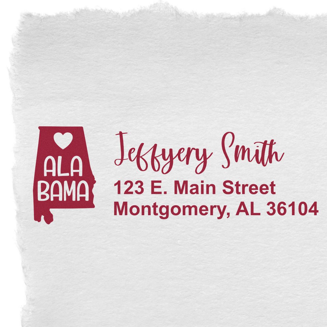 Slim Alabama Custom Address Stamp for Envelopes displayed on textured paper, featuring a red Alabama state outline with heart and personalized address in elegant font.