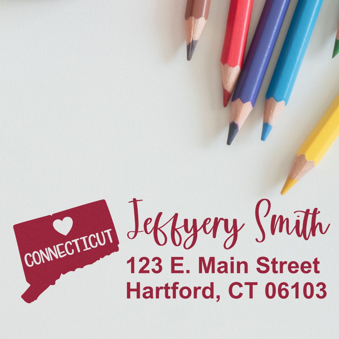 PSI Pre-Inked Connecticut State Love Customized Address Stamp on paper with colored pencils. Displays Connecticut with a heart and personalized address: 123 E. Main Street, Hartford, CT 06103.