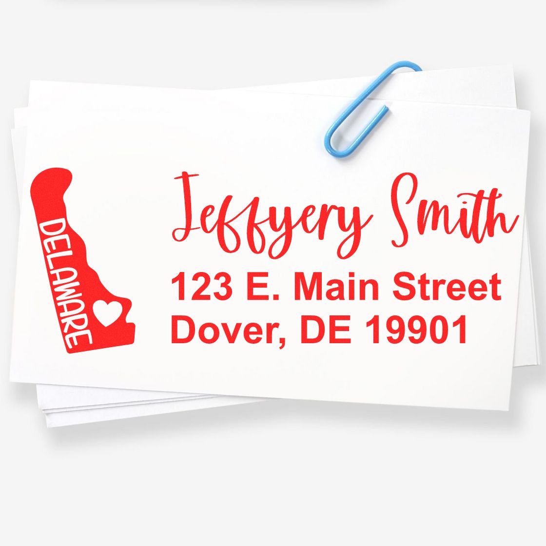 State Love of Delaware Custom Address Stamp Self-Inking displayed on white envelopes with red text and a Delaware state outline, featuring a heart symbol. Includes name and address details.