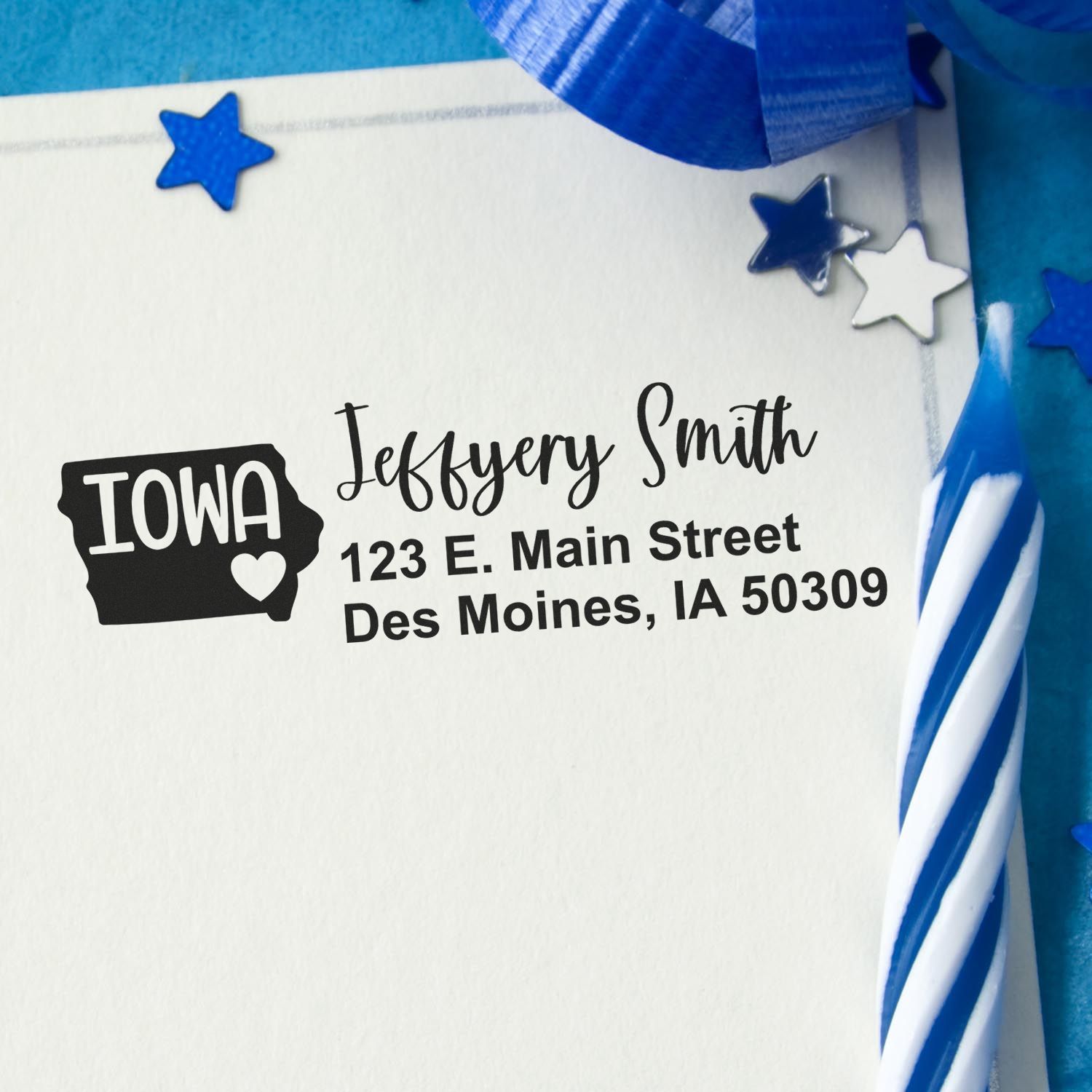 Iowa State Love Personalized Address Stamp on an envelope with a blue candle and star decorations. The stamp features a heart and the state outline, displaying a name and address in Des Moines, IA.