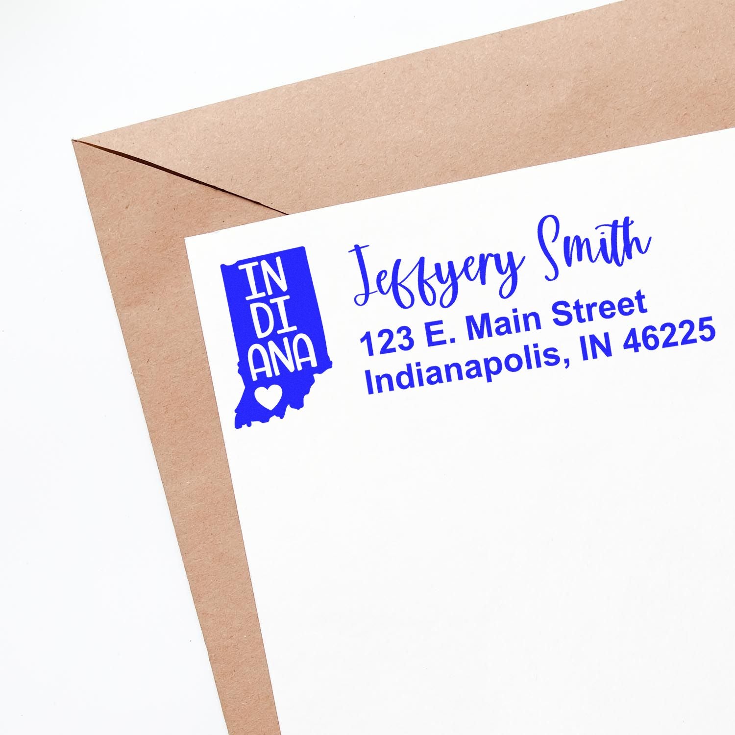 PSI Pre-Inked Indiana State Love Customized Address Stamp on a white envelope with blue ink, featuring an Indiana state outline and heart, next to a brown envelope.