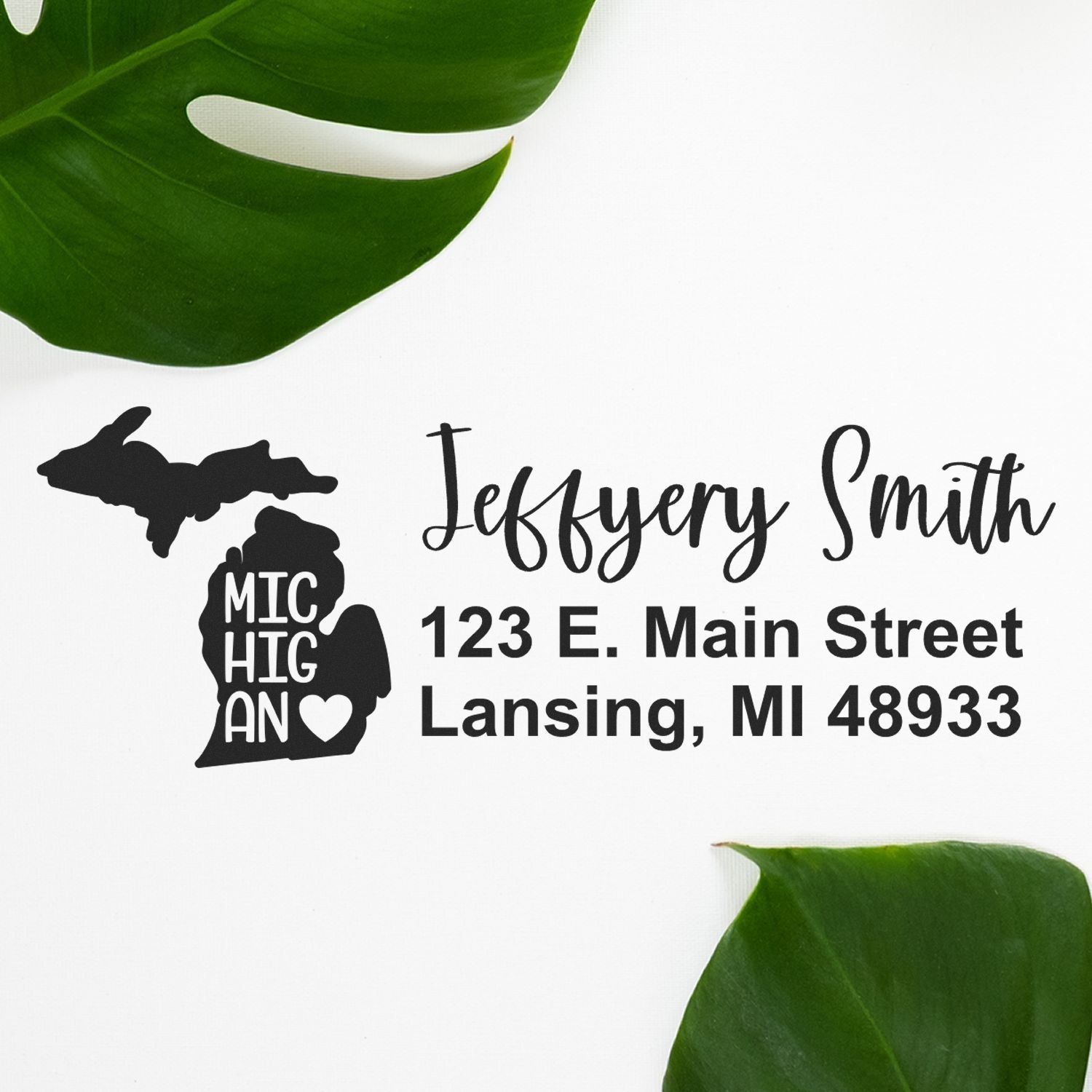 PSI Pre-Inked Michigan State Love Customized Address Stamp featuring 'Michigan' with a heart, personalized with 'Jeffery Smith, 123 E. Main Street, Lansing, MI 48933' on a white background with green leaves.