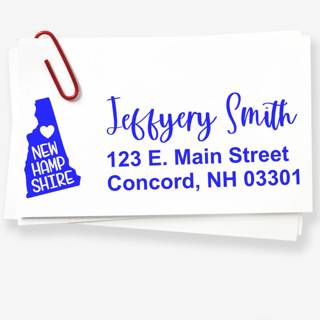 New Hampshire State Love Personalized Address Stamp on white paper with blue text, featuring a state outline and heart. Includes name, street, city, and zip code. Red paperclip attached.